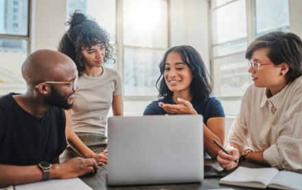 Group of young people gathered around a computer talking
