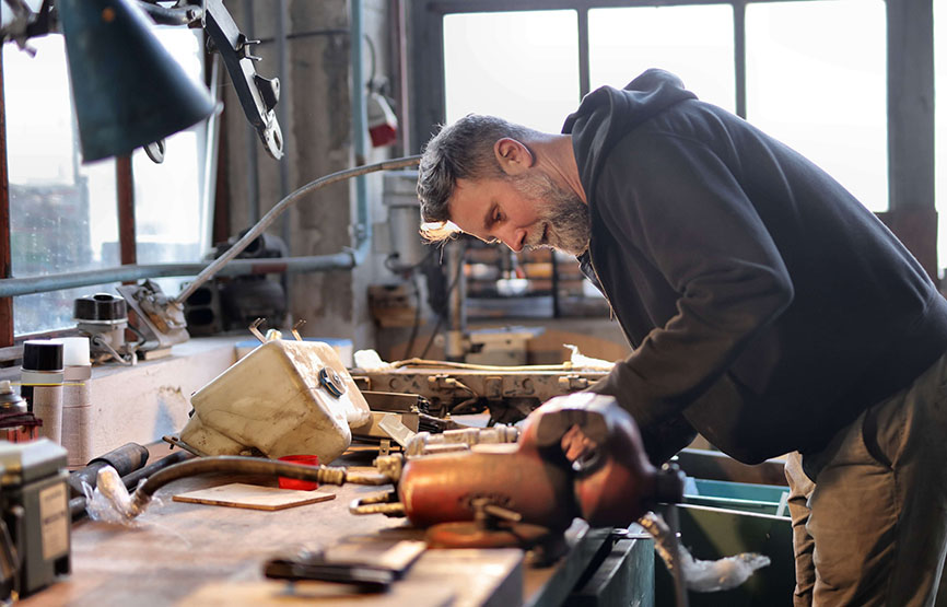 A photo of a man with a beard standing over a work bench with tools and hardware.