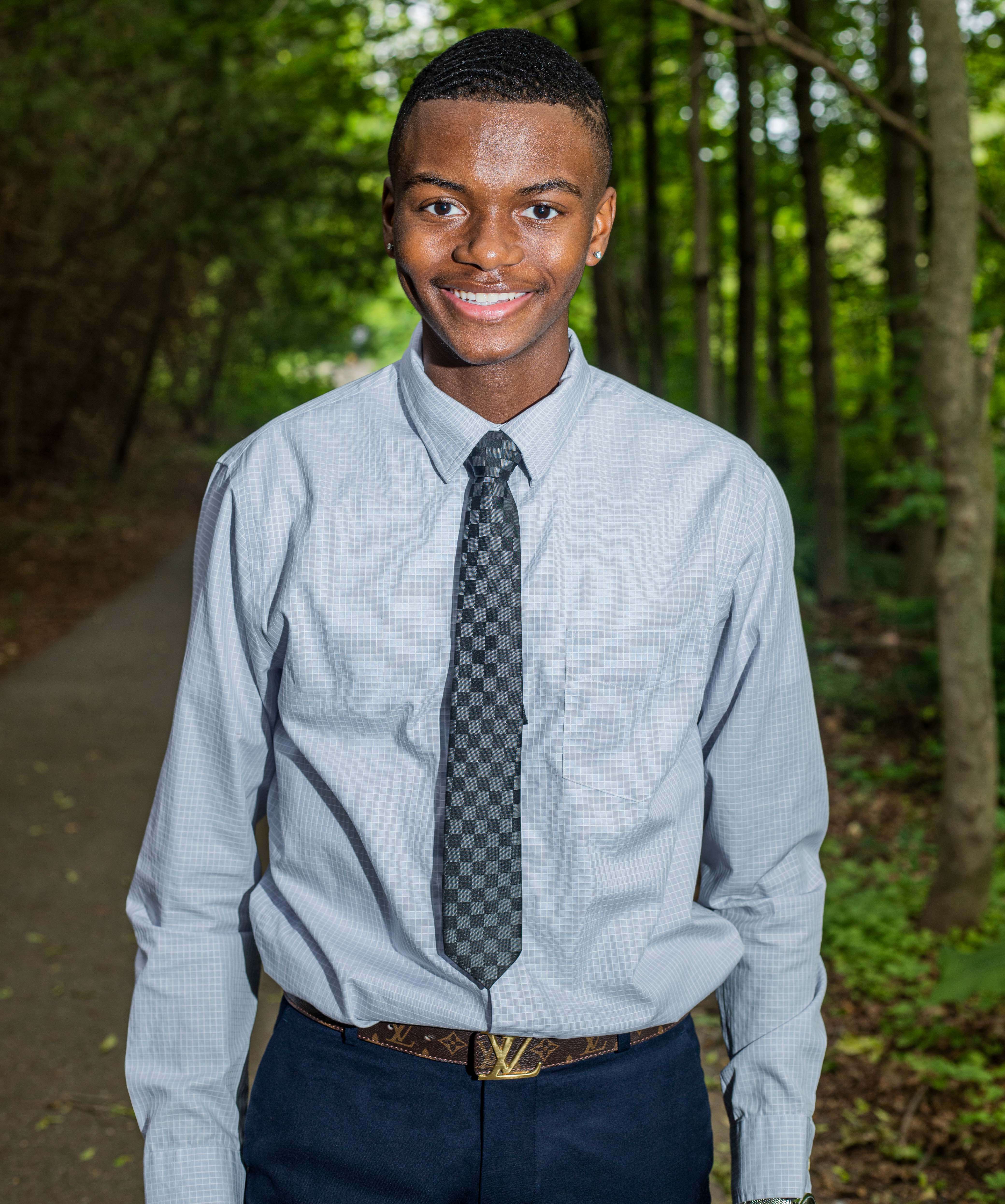 A photo of Miles Leslie, smiling outdoors wearing a blue shirt and tie.